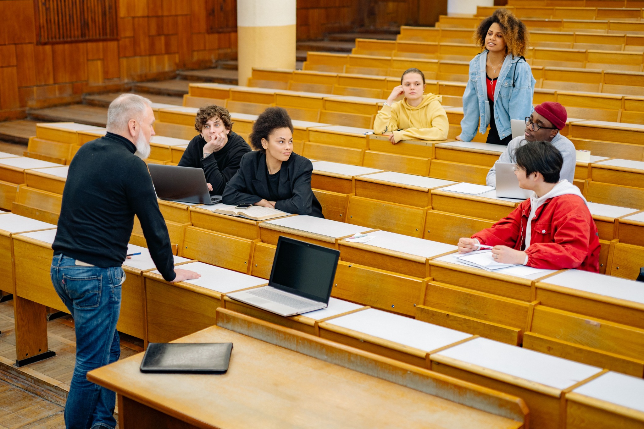 College students and an instructor discuss coursework in a lecture hall.