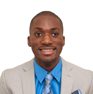 Man in a light gray suit with a blue shirt and striped tie, smiling directly at the camera against a plain white background.